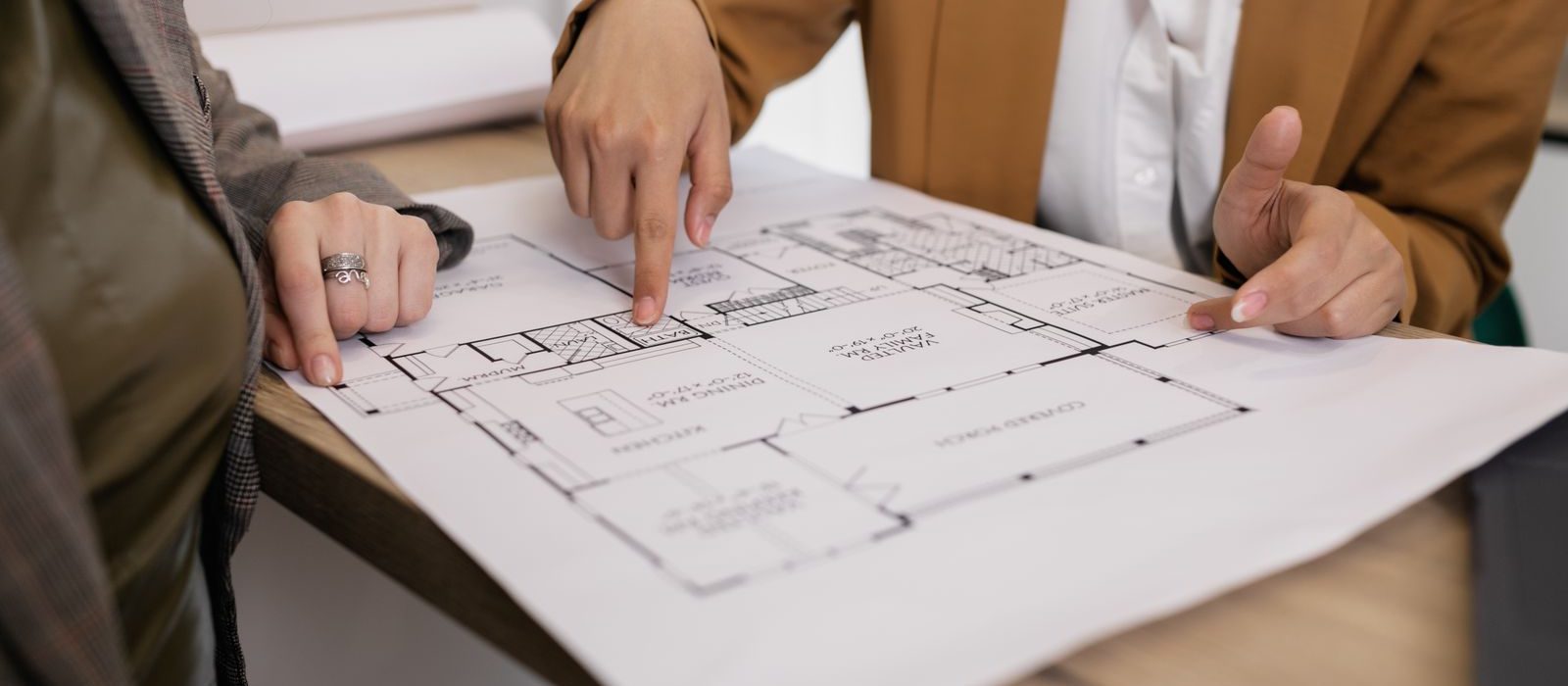 Two people reviewing building plans across a table